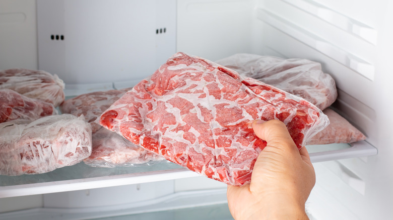 Hand taking frozen meat from the freezer