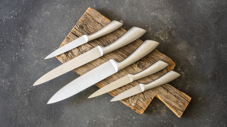 Set of five kitchen knives on wood chopping board