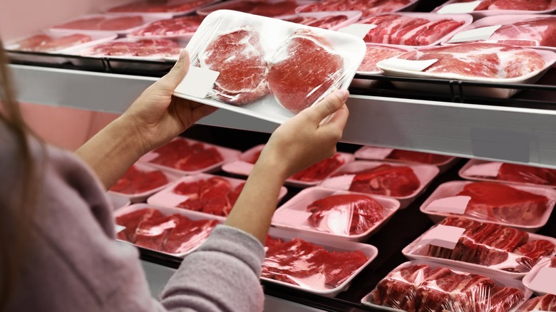 woman examining grocery store meat