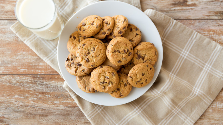 Chocolate chip cookies on a plate with a glass of milk