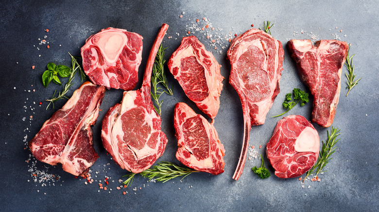 Different cuts of steaks with herbs and garnishes.