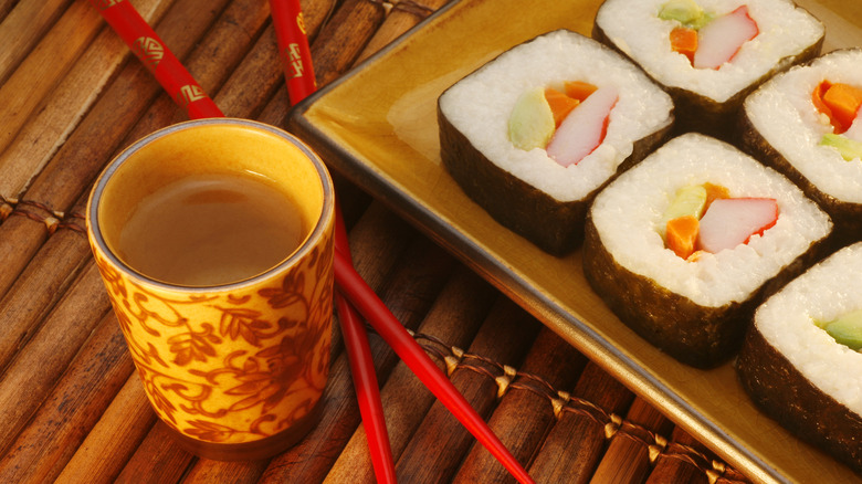 A cup of sake beside a platter of sushi
