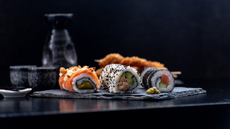 A plate of sushi with sake in the background