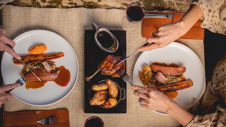hands cutting into roast meat