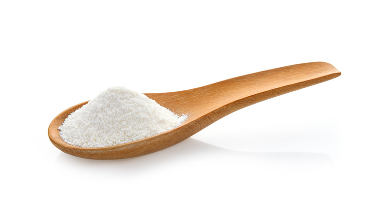 Powdered coffee creamer on a wooden spoon