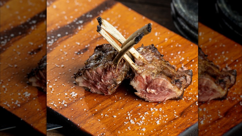 Grilled lamb sits on a wooden board