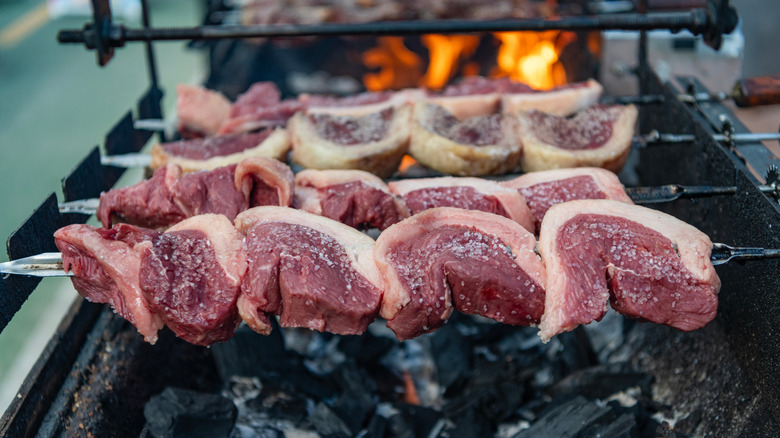 Skewers of raw picanha on a churrasco grill