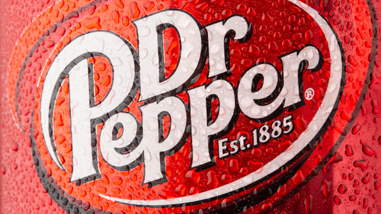 A close-up of the Dr. Pepper logo on a red can with condensation on it