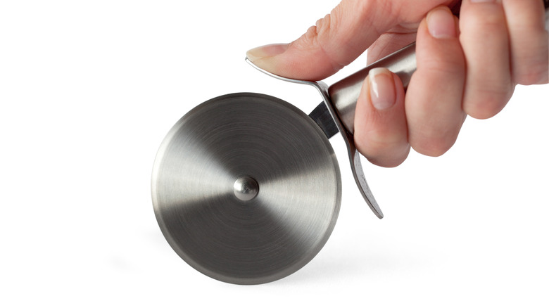 hand holding pizza cutter