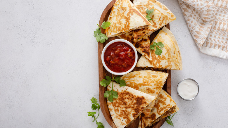 Quesadillas on board with bowl of salsa