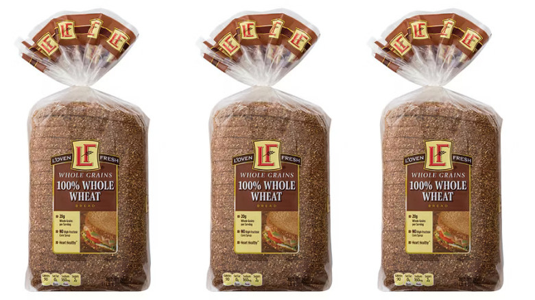 three bagged loaves of Aldi L'Oven Fresh whole wheat bread against a white background