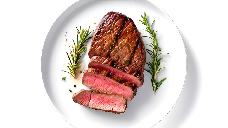 Sliced steak and rosemary on plate 