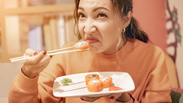 woman sniffing bad sushi roll