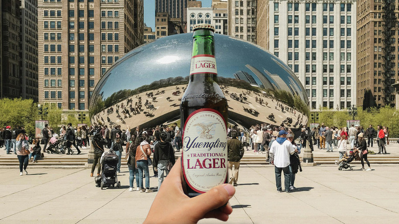 Hand holding bottle of Yuengling in front of the Chicago Bean